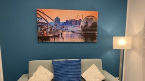 A room with a light grey sofa, two patterned cushions, a cityscape painting, and a floor lamp. - The Comfortable House 2 (Genova)