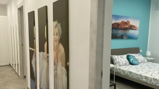A hotel room with a bed, a nightstand, a lamp, and a wall with a painting. - The Comfortable House 2 (Genova)
