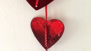 A red heart-shaped decoration hanging from a white wall. - Sunny, cosy and quiet appartment with a view to Salzburg, close to the city (Ainring)