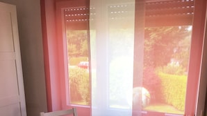 A small dining area with a table and two chairs, a potted plant on the table, and a window with blinds. - Sunny, cosy and quiet appartment with a view to Salzburg, close to the city (Ainring)