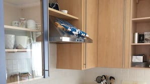 A kitchen with wooden cabinets, a stainless steel range hood, a built-in oven, and a coffee machine. - Sunny, cosy and quiet appartment with a view to Salzburg, close to the city (Ainring)