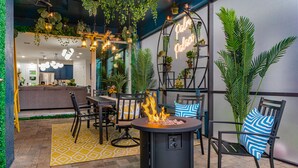 Un espace extérieur aménagé en terrasse, avec un foyer, des sièges et des plantes en pot.