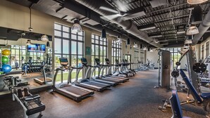 Une salle de sport équipée de tapis de course, d’appareils de musculation et de ballons d’exercice.