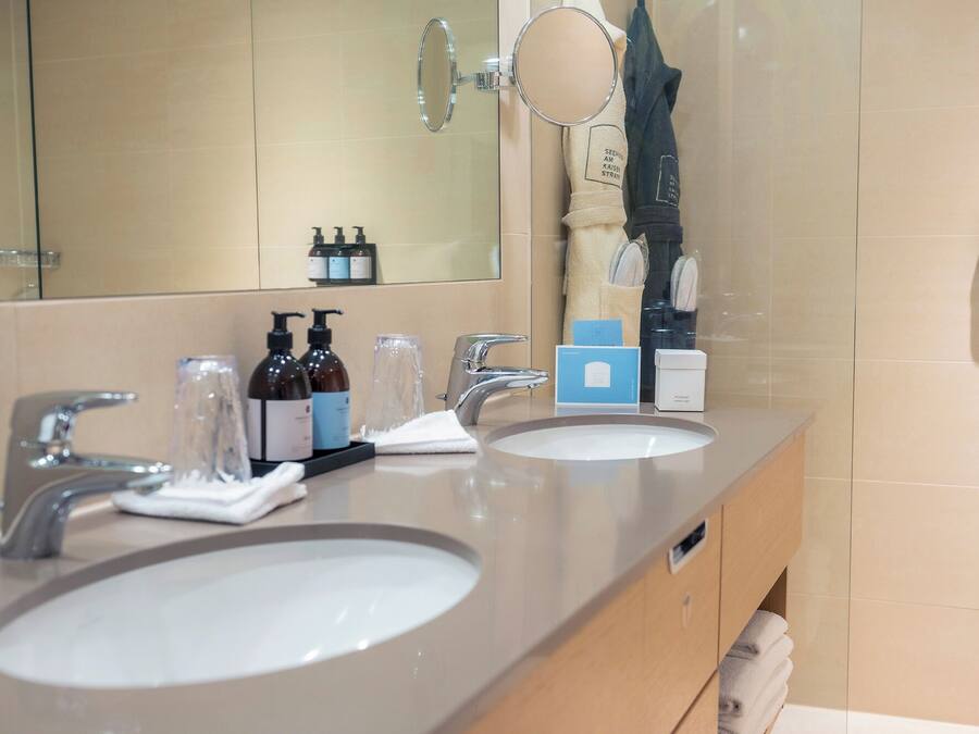 A bathroom with two sinks, a mirror, and toiletries.