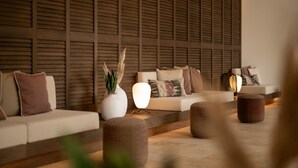 Un espacio lounge moderno con un muro de listones de madera, un conjunto de sofás y una lámpara de pie.