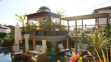 Un espace piscine aménagé sur le toit, avec des chaises longues, une pergola et des plantes en pot.
