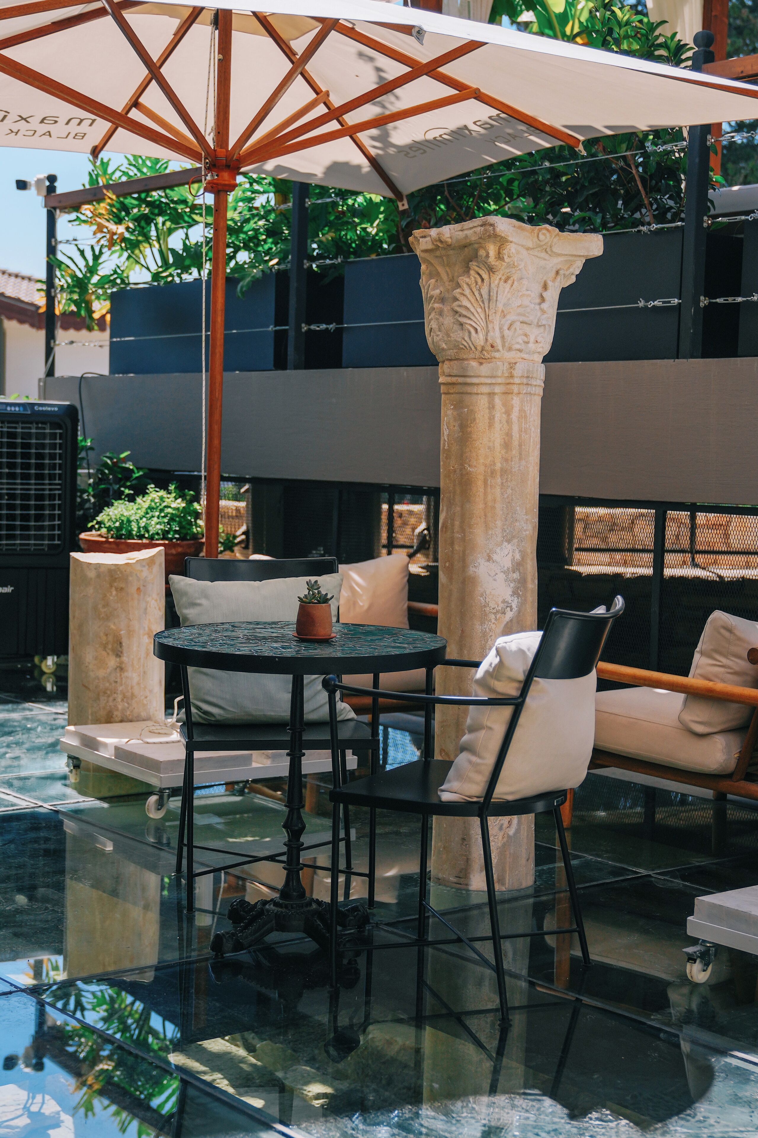 Un espace extérieur aménagé avec une table ronde, des chaises et un grand parasol.