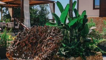 Un espacio al aire libre rústico con una silla de madera original, rodeado de exuberante follaje y una jardinera de piedra.