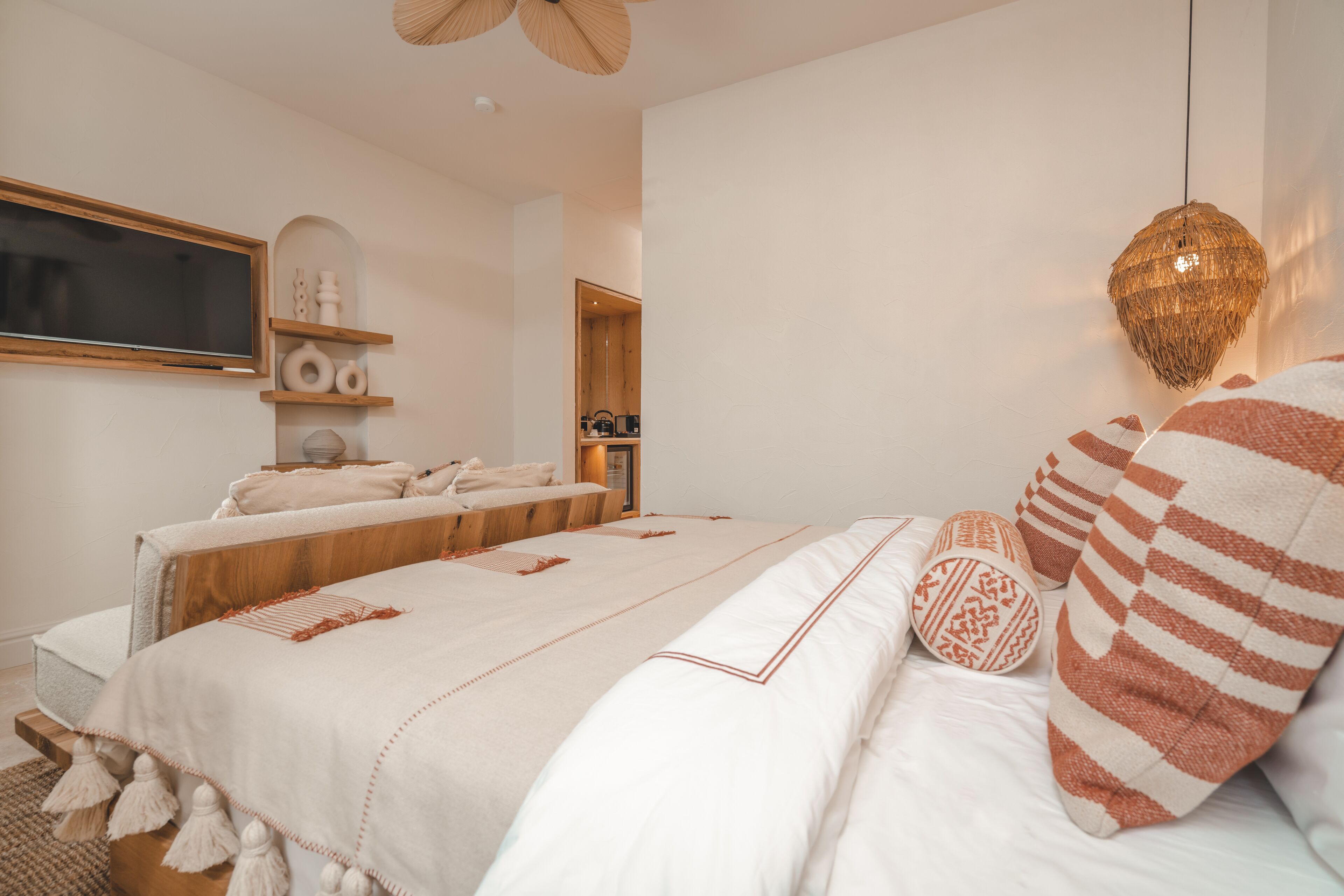 A bedroom with a large bed, a wooden headboard, a bedside table, and a hanging light fixture.