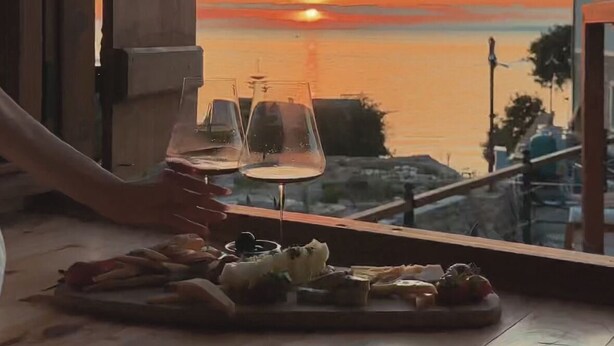 Udsigt fra et vindue med et bord dækket til to personer, med et glas vin og en ostebakke.