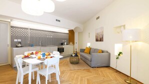 A modern kitchen with a dining area, a sofa, and a floor lamp. - Sweett | Maison Laghetto (Milano)