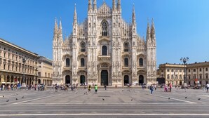 A large cathedral with a central dome and multiple spires, surrounded by a spacious plaza with people and pigeons. - Sweett | Maison Laghetto (Milano)