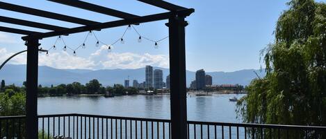 A covered outdoor area with a view of a lake, a city skyline, and mountains in the distance.