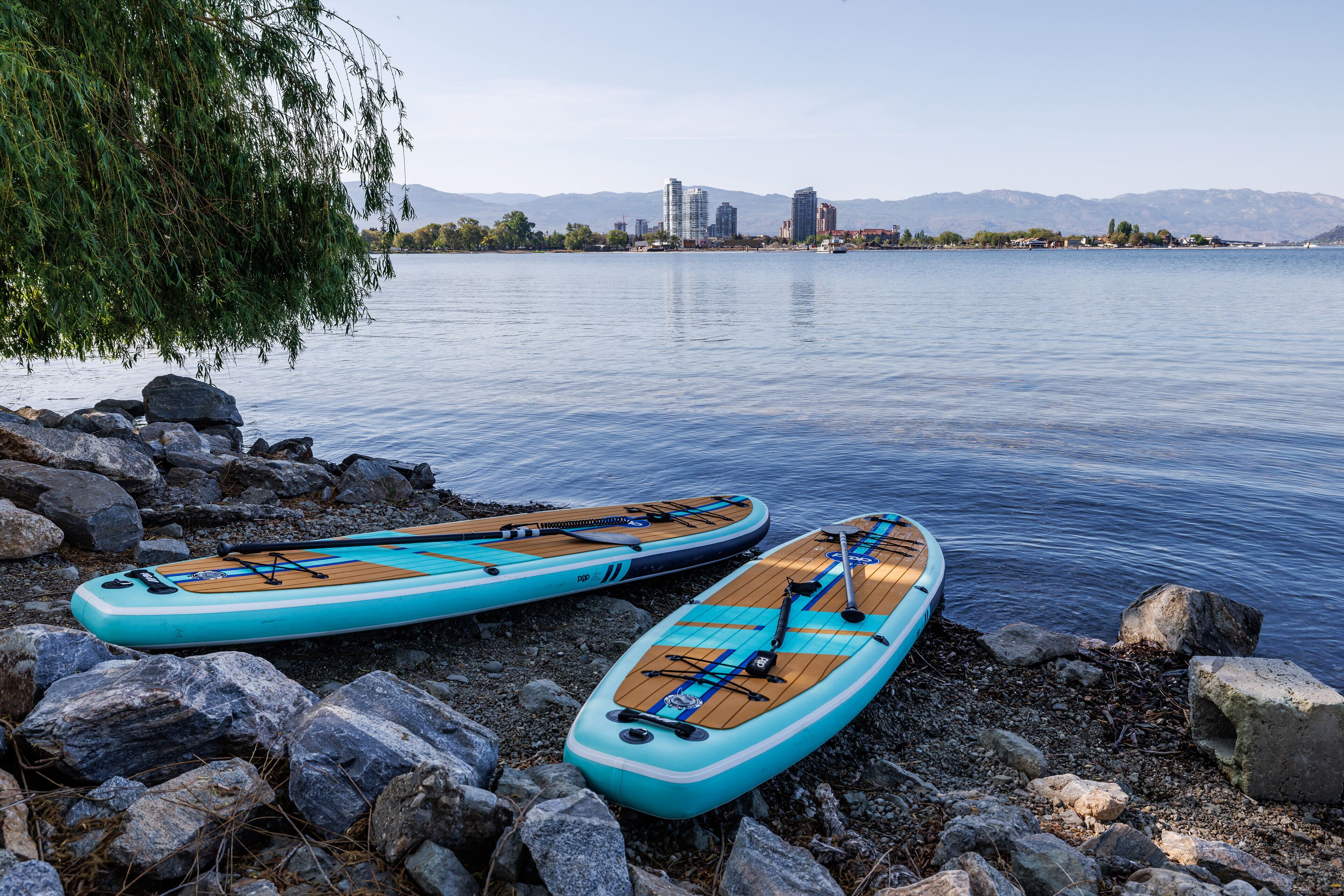 Two kayaks on a rocky shore by a calm lake with mountains in the background.