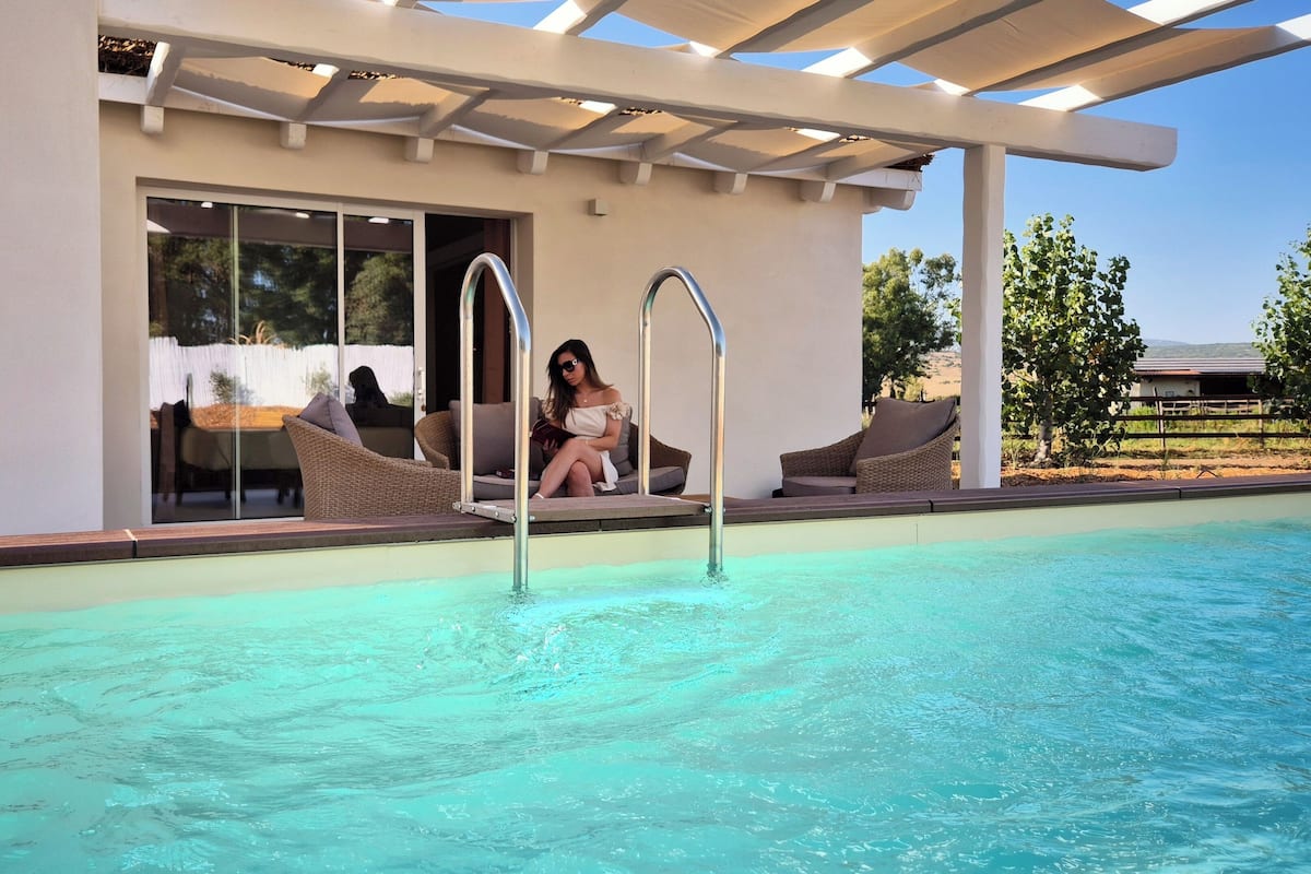 A pool area with a glass enclosure, outdoor seating, and a pergola structure.