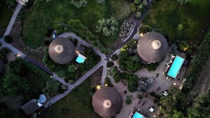 Vista aérea de un complejo turístico con tres estructuras de techo redondeado, una piscina y un jardín bien cuidado.