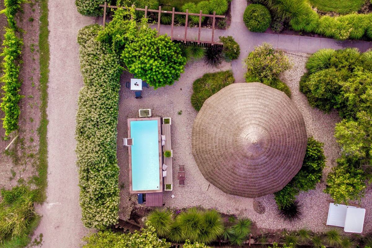 An aerial view of a garden with a circular structure, a rectangular pool, and a wooden deck.
