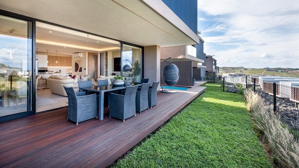 Un espacio exterior moderno con terraza de madera, mobiliario exterior y vistas al paisaje.