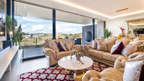 Una sala de estar moderna con un ventanal grande, sofás de cuero, una mesa de centro blanca y una figurita decorativa de un perro.