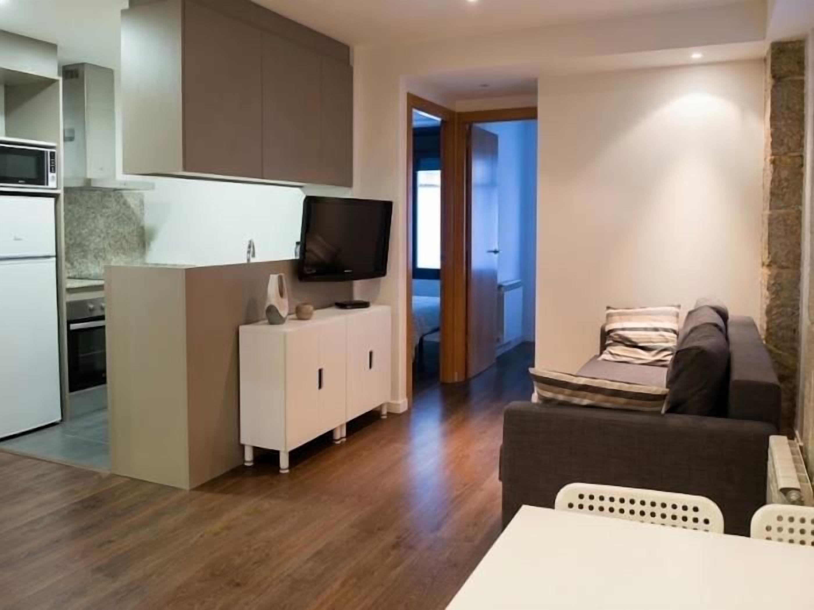 Un espacio habitable compacto con kitchenette, televisor de pantalla plana, sofá y zona de comedor.