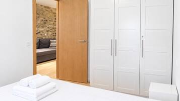 Un dormitorio con una cama, un armario de madera y una pared de piedra al fondo.