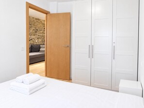 Une chambre à coucher avec un lit, une armoire en bois et un mur en pierre en arrière-plan.