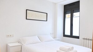 Ein schlicht eingerichtetes Schlafzimmer mit Bett, Nachttisch und einem gerahmten Bild an der Wand.