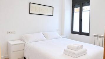 Un dormitorio minimalista con cama, mesita de noche y un cuadro en la pared.