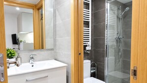 Ein modernes Badezimmer mit einem weißen Waschbecken, einer Toilette und einer Duschkabine.