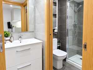 Une salle de bain moderne avec un lavabo blanc, des toilettes et une douche à parois de verre.
