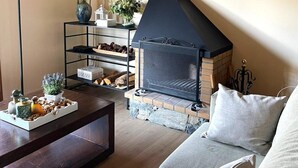 Ein gemütliches Wohnzimmer mit Kamin, einem Holztisch, einer Couch und einem Regal mit Dekoration.