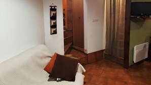 A small, cozy room with a bed, a wooden door, and a radiator. - House 2 rooms Fireplace, Charm and Views, 5km from Llívia (Saillagouse)
