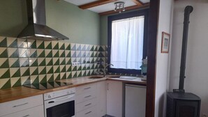 A compact kitchen with a stove, oven, and a wood-burning stove. - House 2 rooms Fireplace, Charm and Views, 5km from Llívia (Saillagouse)