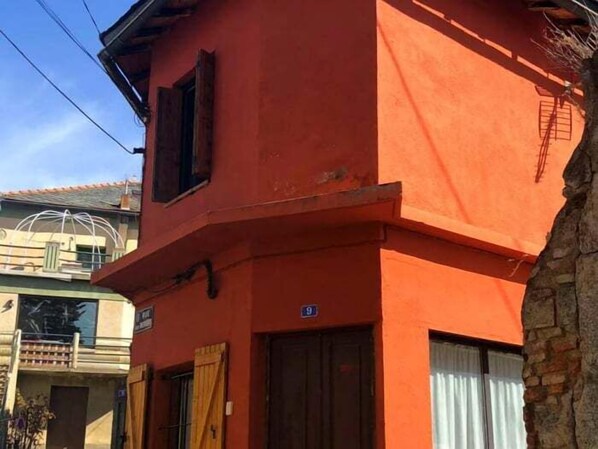 A red building with a wooden door and a window with a curtain.
