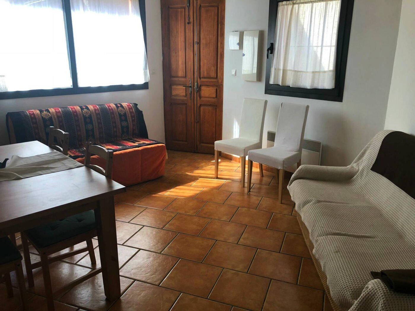 Una habitación con una mesa de comedor de madera, sillas, un sofá y una ventana con cortinas.