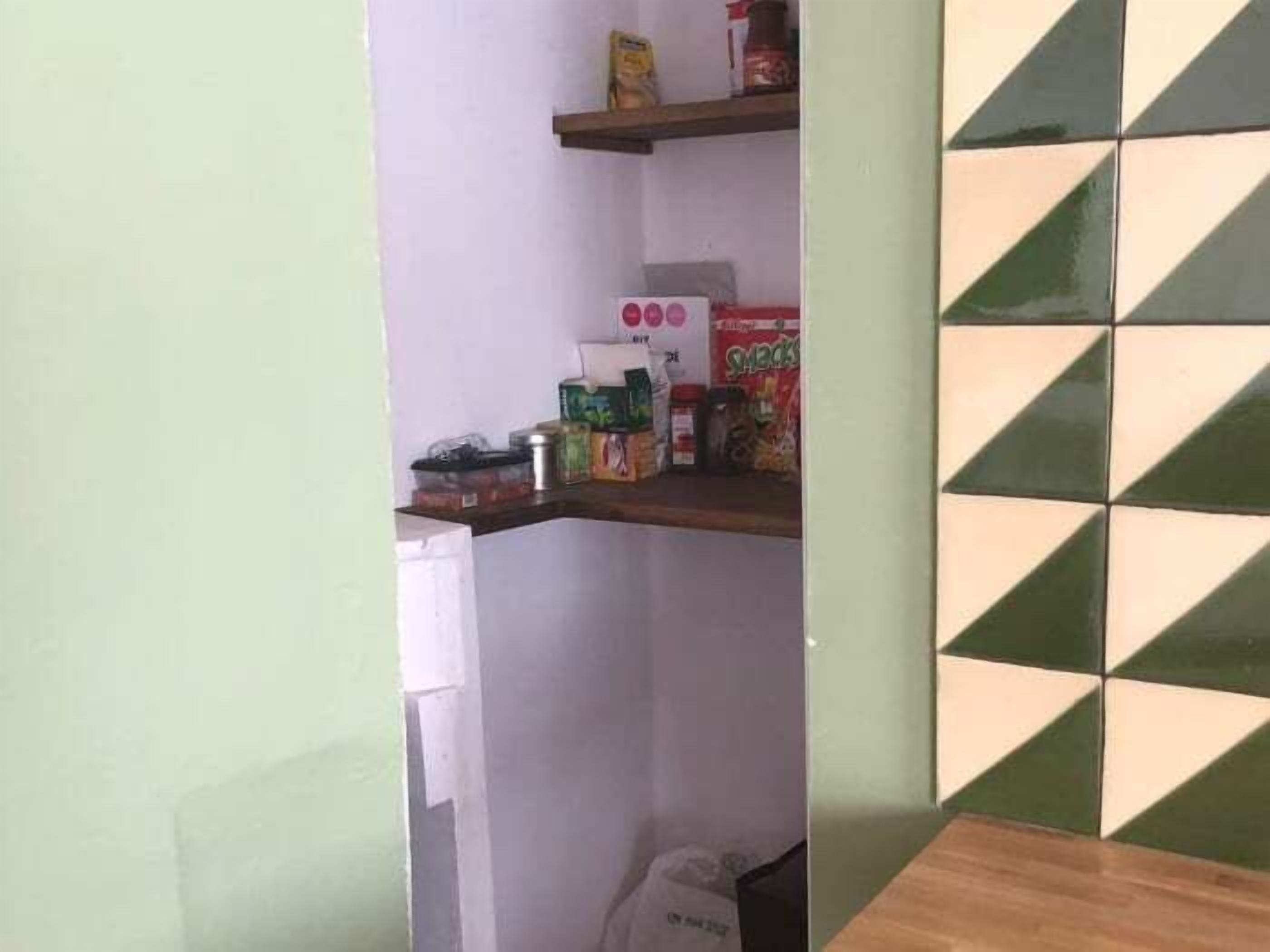 Eine Küche mit einer Holzauskleidung, einem weißen Kühlschrank und Regalen mit verschiedenen Lebensmitteln.