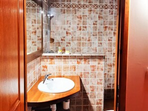 A bathroom with a wooden vanity, a white sink, and a tiled backsplash.