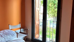 A bedroom with a bed, a chair, and a large window with a view of greenery outside. - House 2 rooms Fireplace, Charm and Views, 5km from Llívia (Saillagouse)