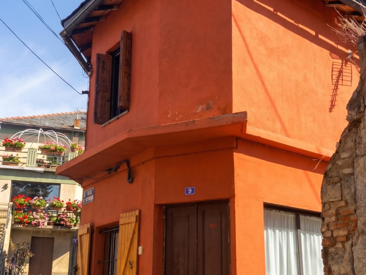 Un edifici amb una porta de fusta i un balcó amb plantes en testos.