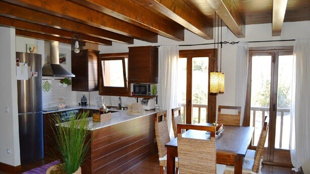 A modern kitchen with wooden beams, stainless steel appliances, and a dining area with woven chairs. - Ground Floor 3 rooms Pool, Fireplace, Garden & Wi-Fi (Queixans)