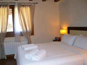 A hotel room with a bed, a nightstand, a lamp, and a window with curtains.