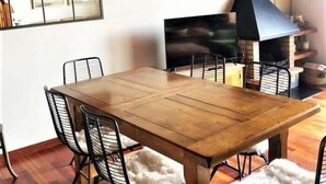 A dining area with a wooden table and black wire chairs, a fireplace, and a mirror on the wall.