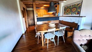 A cozy dining area with a wooden table and chairs, a bench, and a tufted sofa. - Ground Floor 3 rooms Pool, Fireplace, Private Garden & Views (Olopte)
