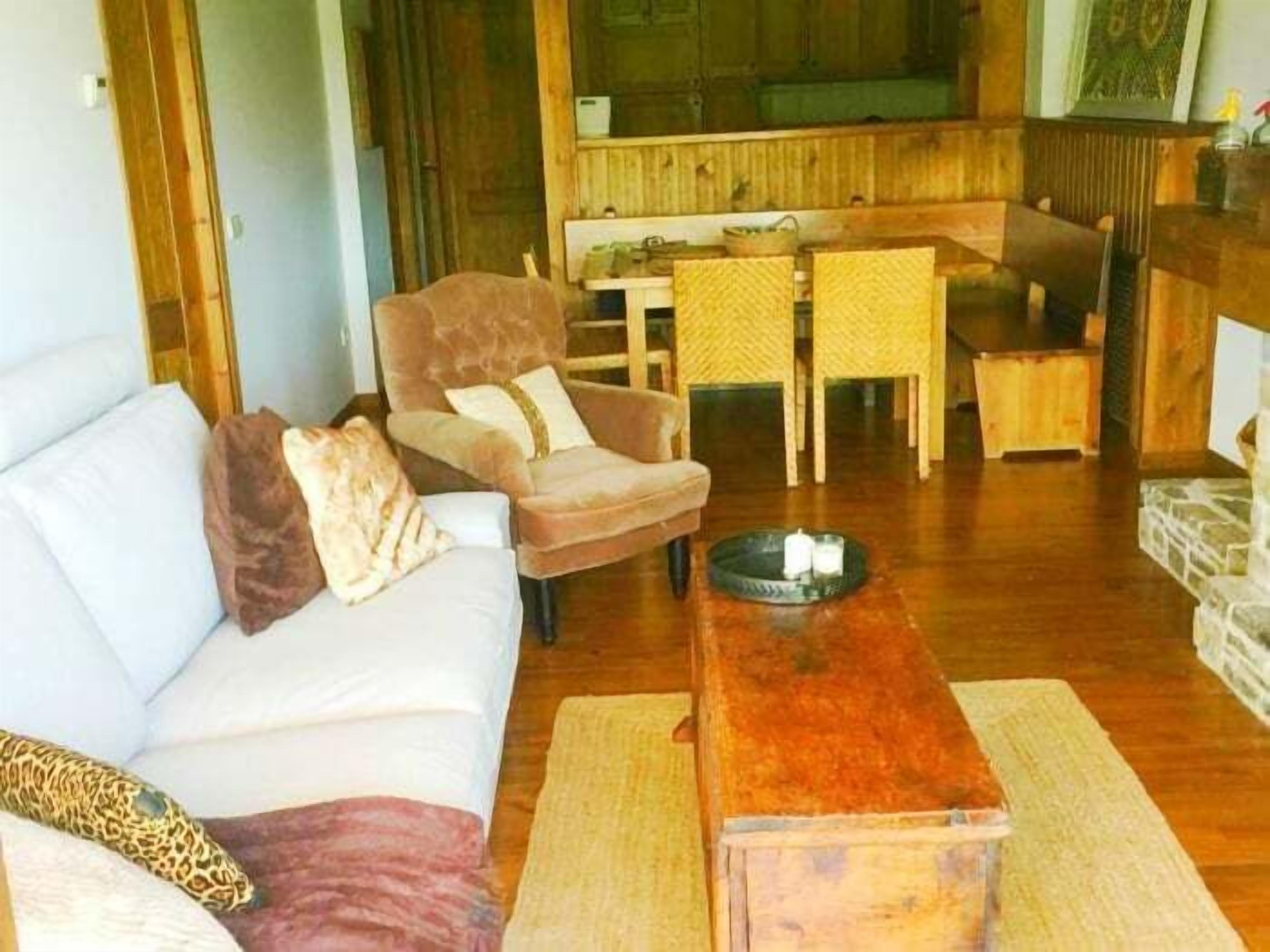 A living room with a sofa, armchair, dining table, and chairs.