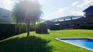 A backyard with a swimming pool, neatly trimmed hedges, and a large tree providing shade. - Ground Floor 3 rooms Pool, Fireplace, Private Garden & Views (Olopte)