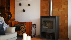 A cozy living room with a fireplace, a sofa, a wooden cabinet, and a table with candles.