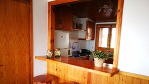 A kitchen with wooden cabinets, a sink, and two stools.
