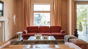 A living room with a red sofa, a white coffee table, and a patterned rug. - Bellwether House Summ (Louisville)