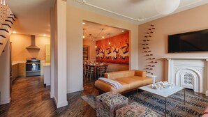 A modern living room with a sofa, ottomans, a fireplace, and a television. - Bellwether House Summ (Louisville)