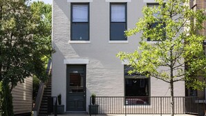 A two-story building with a gray facade, a black front door, and a visible address number. - Bellwether House Summ (Louisville)